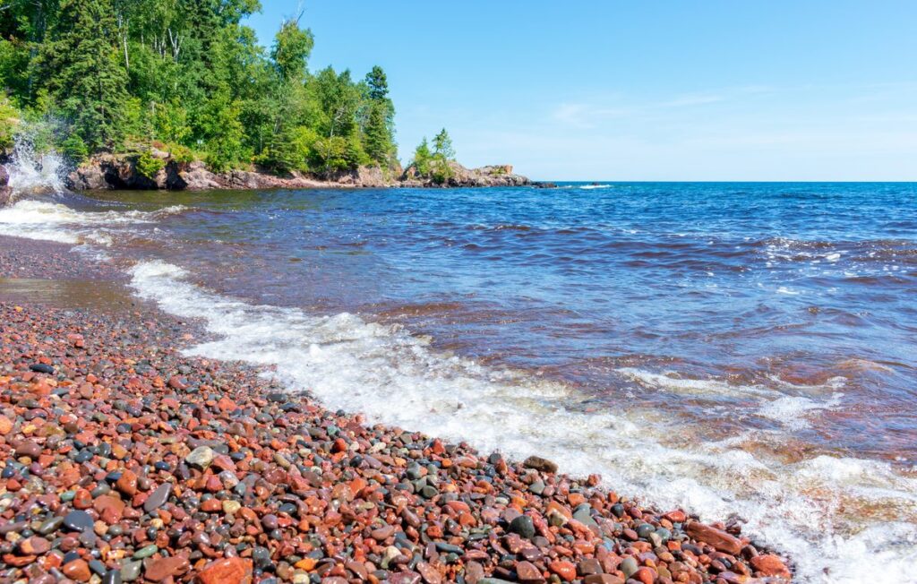 Red and multicolored pebble beach along the Lake Superior shoreline on a clear day
