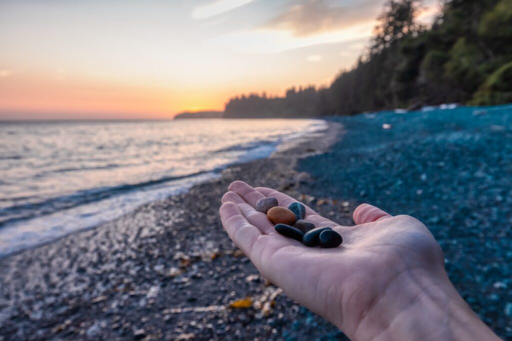 A beachcomber holding a handful of polished Lake Superior stones at sunset